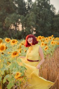 woman in yellow sleeveless dress standing on sunflower field during daytime