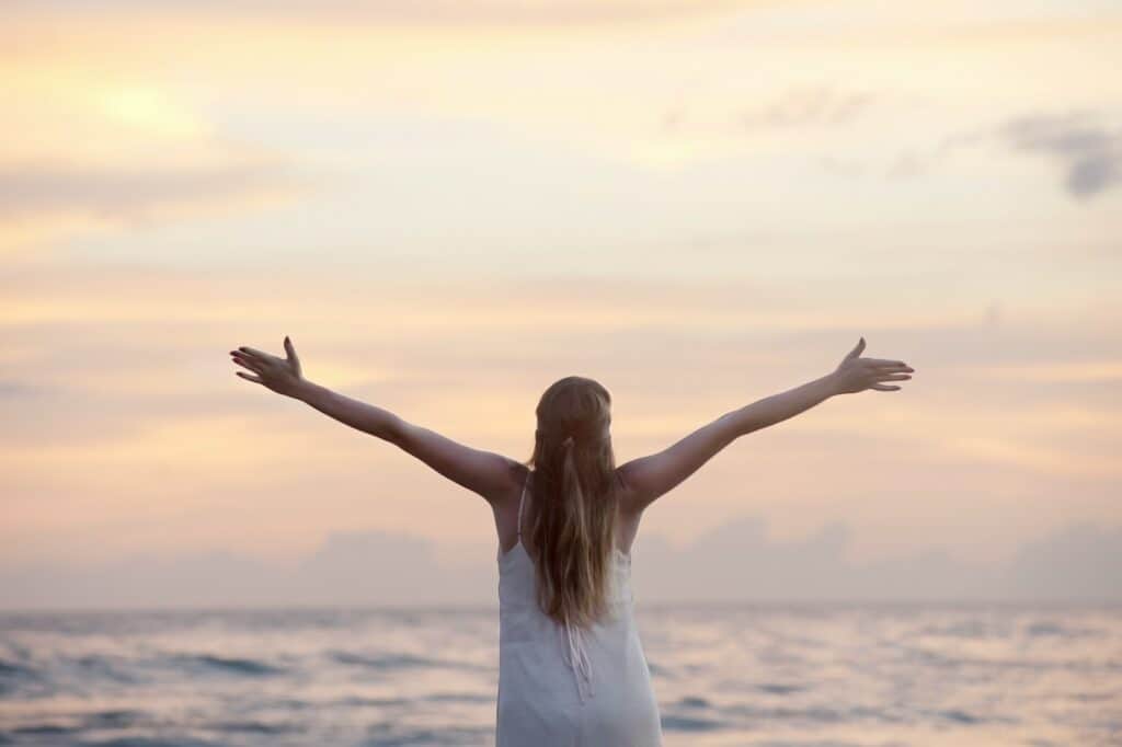 Rear View of Woman With Arms Raised at Beach during Sunset, grateful