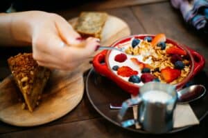 breakfast, Person Holding Spoon and Round Red Ceramic Bowl With Pastries