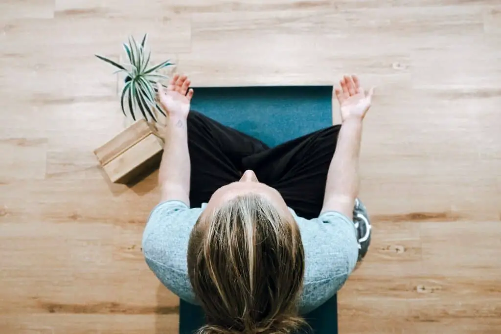 woman in black shirt and gray pants sitting on brown wooden bench, mindfulness