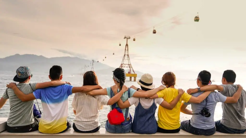 people holding shoulders sitting on wall, friends