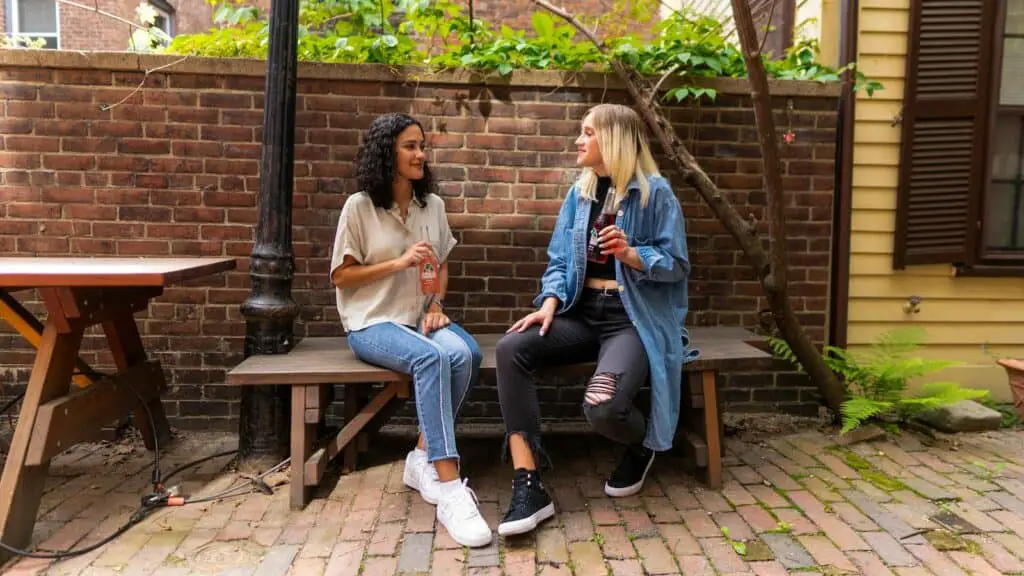 2 women sitting on brown wooden bench, active listening