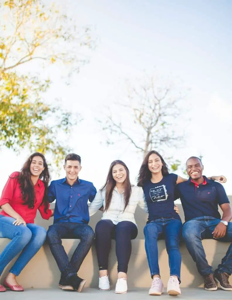 group of people sitting on bench near trees duting daytime, laughter