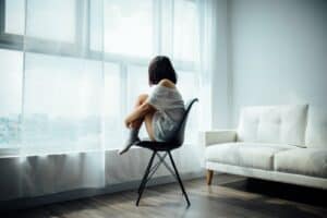 woman sitting on black chair in front of glass-panel window with white curtains