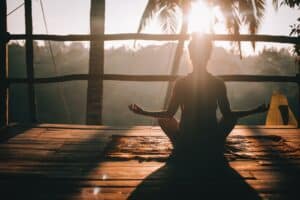 meditate, woman in black tank top sitting on brown wooden dock during daytime