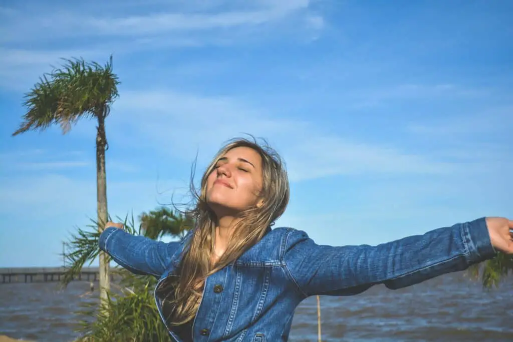 woman spreading arms near body of water, positivity